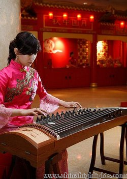 A girl wearing Qipao plays the zither.