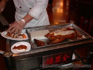 A cook cutting a roasted duck into pieces at Quanjude