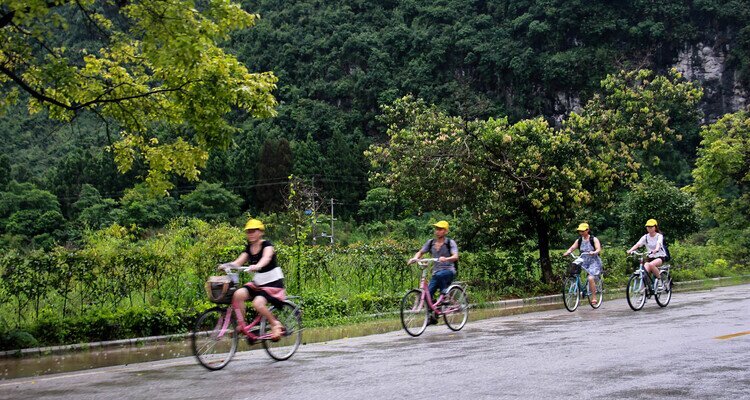 Four young men wearing yellow hats were riding bicycles on a country road in Yangshuo.