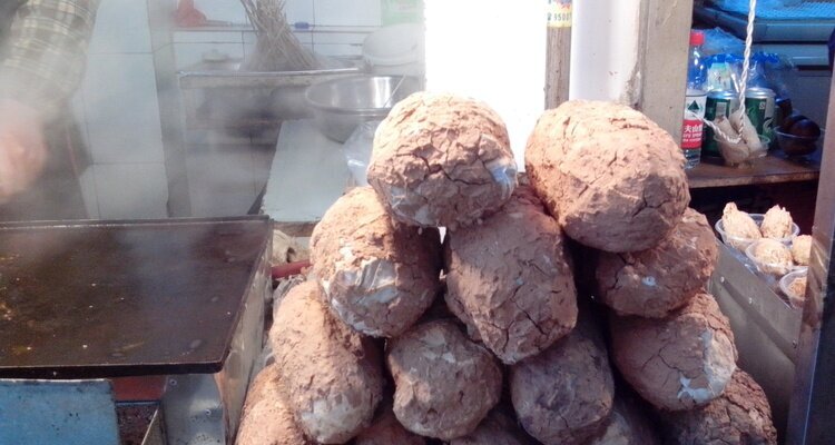 Pollo Jiao Hua envuelto en barro durante su cocción