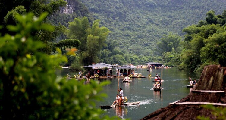 People are enjoying Yulong River bamboo rafting at a cloudy day with cool air in summer