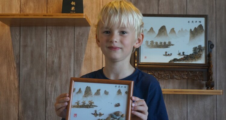 A child proudly holds up his newly finished painting