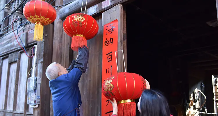 People decorate houses with red lanterns and red couplets.