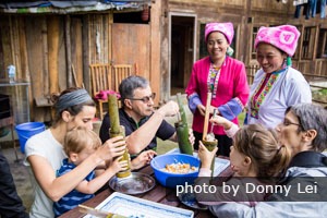 Familia de turistas haciendo arroz en tubos de bambú en las Terrazas de Arroz de Longji en Guilin