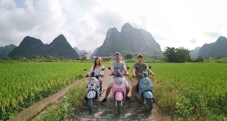 Three tourists tour the Yangshuo countryside on electric bicycles
