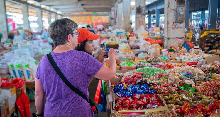 Our tour guide is accompanying international travelers on a tour of the local market.