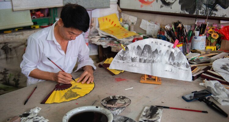 A master is showing how to paint fans in Fuli Ancient Town Yangshuo