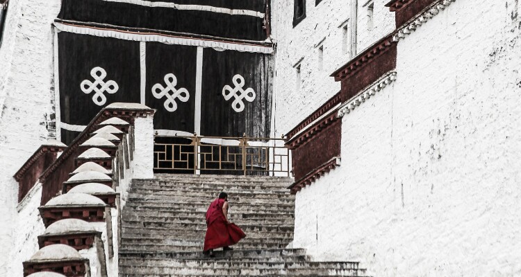 a monk with red dress on Potala Palace