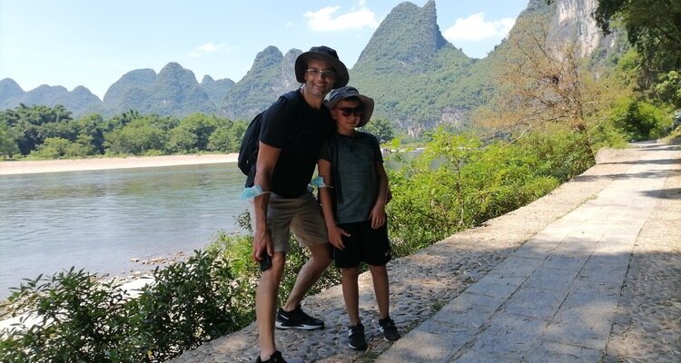 Our(China Highlights) two guests, one adult and one child, took photos on the sunny Li River hiking trail.