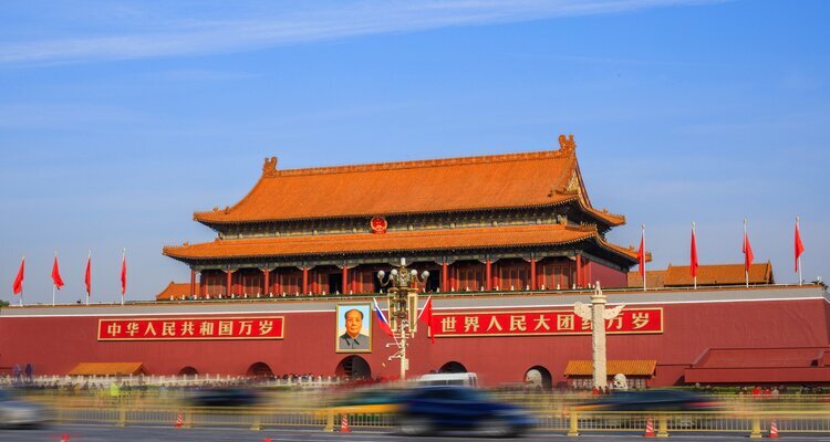 Vista lateral de la Puerta de Tiananmén con tráfico continuo en la avenida bajo cielo azul