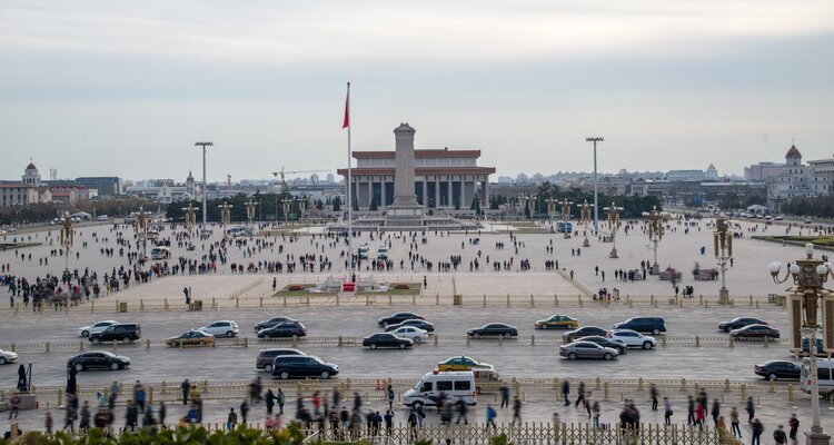 Vista elevada desde la Puerta de Tiananmén sobre la Plaza de Tiananmén con personas, bandera nacional y monumentos