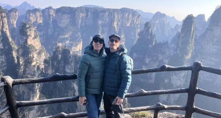 Our two middle-aged white couple are taking a photo in front of Hallelujah Mountain in Zhangjiajie, Hunan, China, in November.